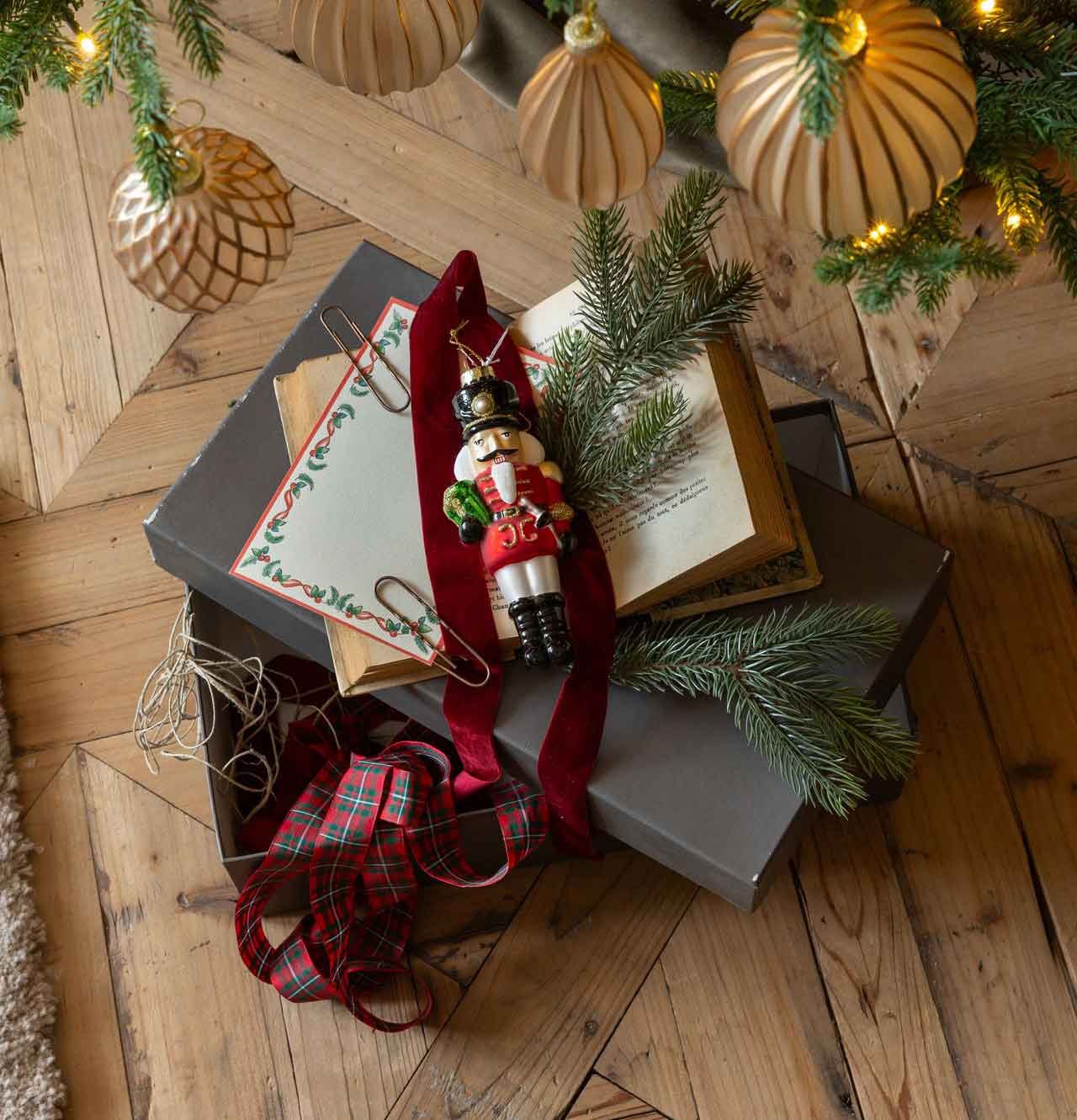 Nussknacker als Christbaumschmuck auf einer Geschenkbox mit Samtband und Tannenzweig