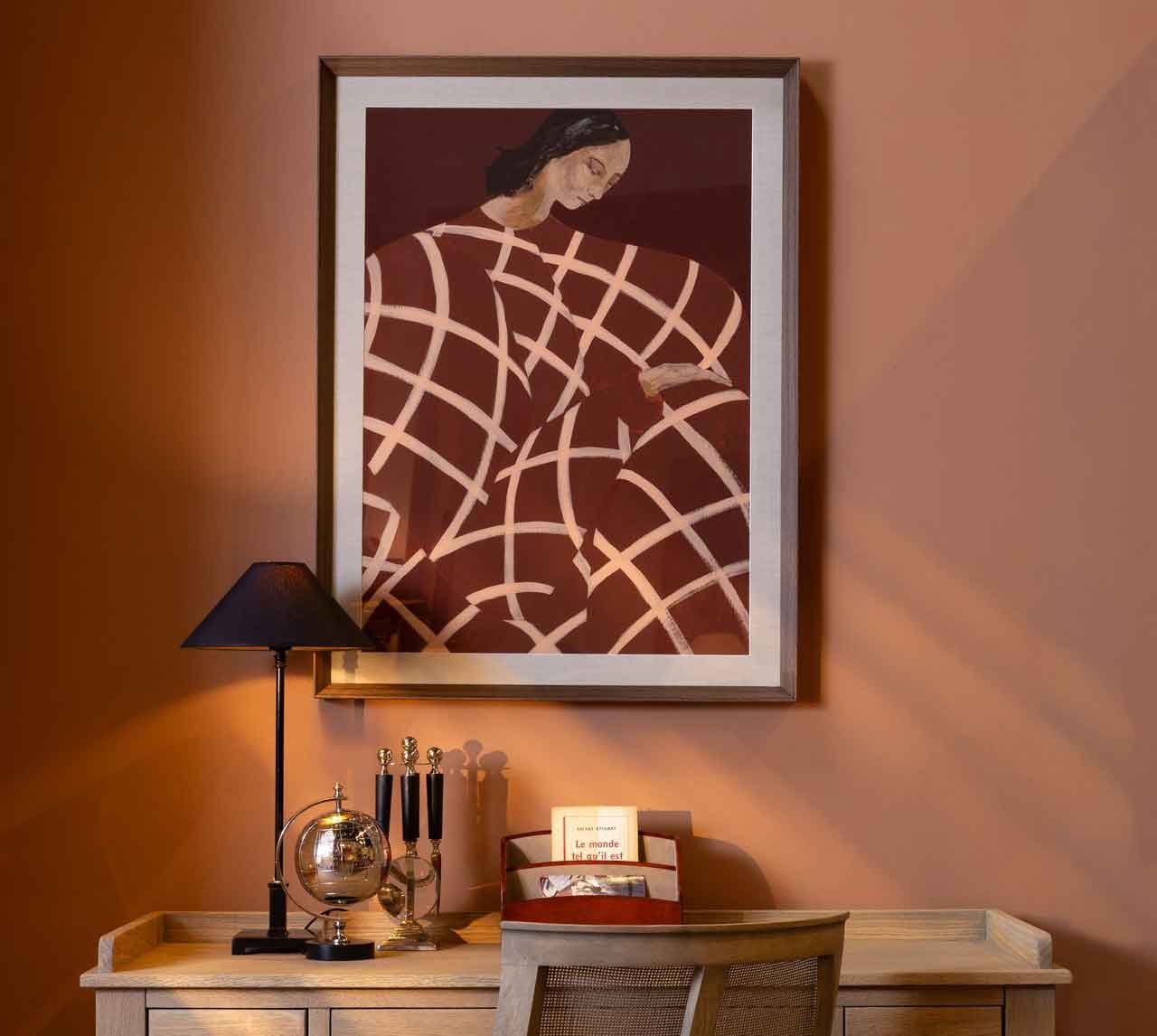 Schreibtisch mit Tischleuchte, Globus und Kunstdruck vor terrakottafarbener Wand