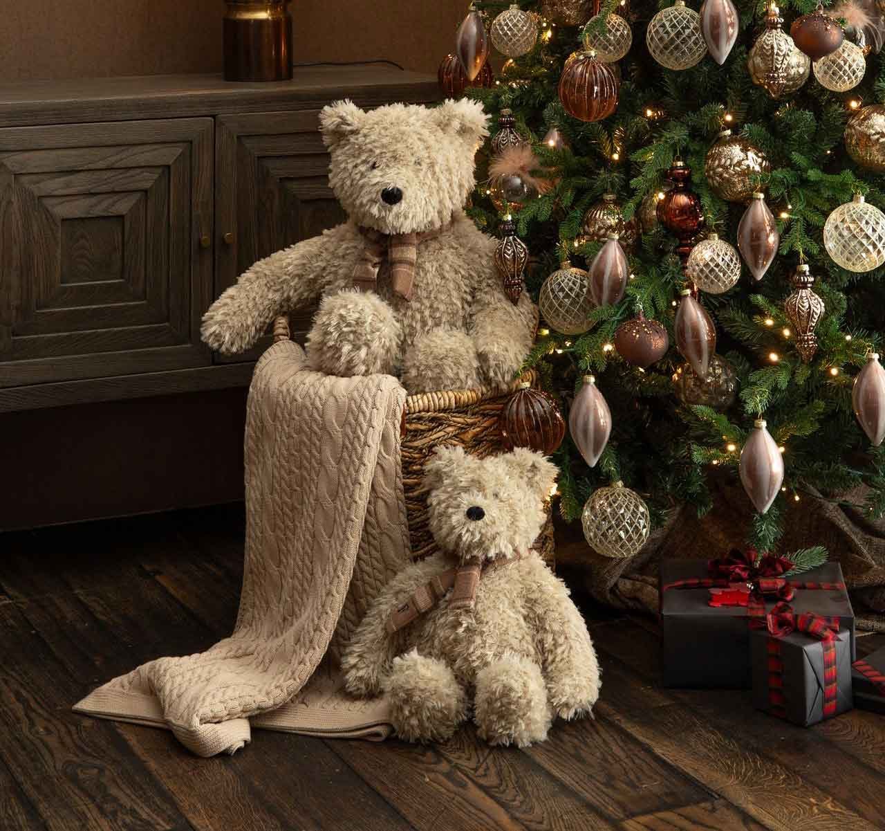 Zwei Teddybären mit Karoschal im Korb unter dem Weihnachtsbaum