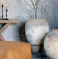 Preview: errakotta-Amphore Antique Creme im Wohnraum mit Lederhocker und Holzkonsole, trockene Äste als Dekoration
