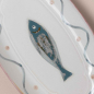 Preview: Ovaler Fayence-Fischteller von oben — blauer Fisch im Zentrum, Wellendekor, Punktemuster, rosafarbener Muschelrand