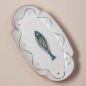Preview: Ovaler Fayence-Fischteller in der Seitenansicht — handgemalter blauer Fisch, Wellenliniendekor, rosafarbener Muschelrand, cremefarbene Glasur