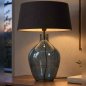 Preview: Glasleuchte Cleria am Abend auf einem Sideboard aus Holz