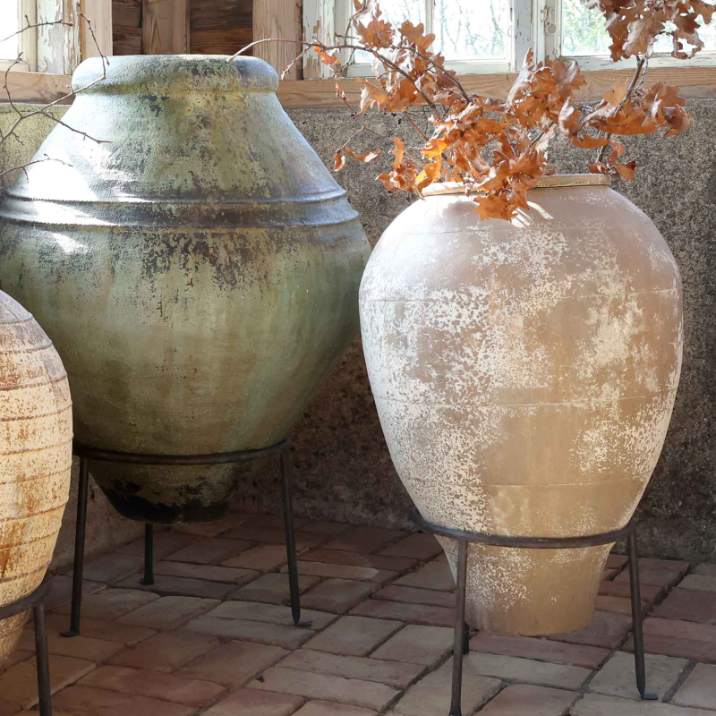 Preview: Terrakotta-Amphore Antique Creme auf Metallgestell neben Antique-Verte-Variante, Ziegelsteinboden