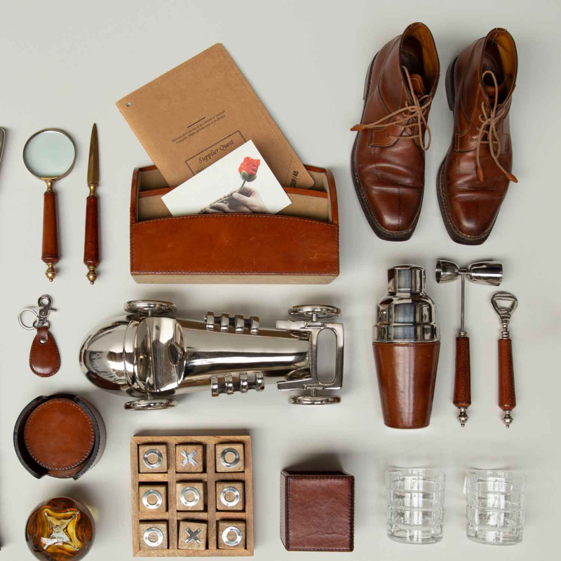Flamant Manhattan Lederkollektion Flatlay mit Cocktailshaker, Lupe, Brieftasche und Rennwagenstatue