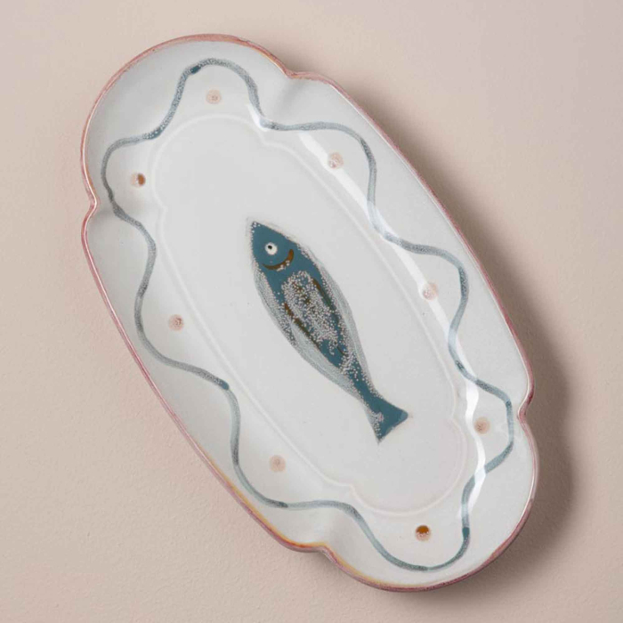 Ovaler Fayence-Fischteller in der Seitenansicht — handgemalter blauer Fisch, Wellenliniendekor, rosafarbener Muschelrand, cremefarbene Glasur
