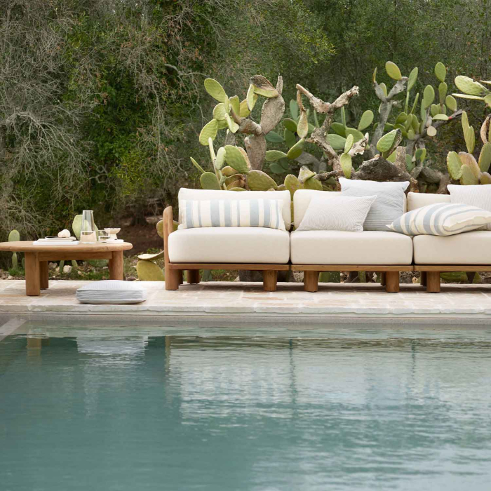 Tine K Teak Modul Sofa dreiteilig am Pool — cremefarbene Kissen mit Streifenkissen, recyceltes FSC-Teak, mediterraner Kaktus-Garten