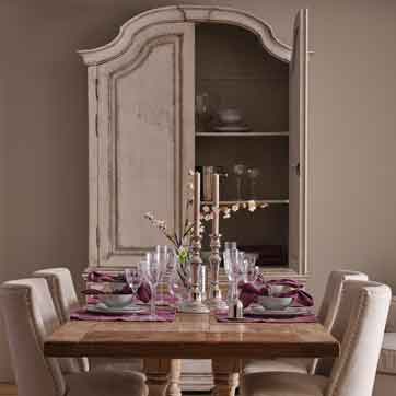 Flamant Esszimmer mit gedecktem Tisch, Leinenstühlen und antikem Vitrinenschrank mit Kalkfarben-Finish