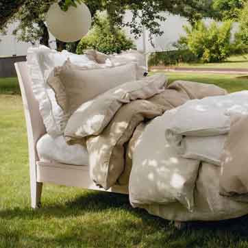 Himla Leinenbettwäsche in Natur-Beige auf einem Bett im Freien, im Garten, locker drapiert